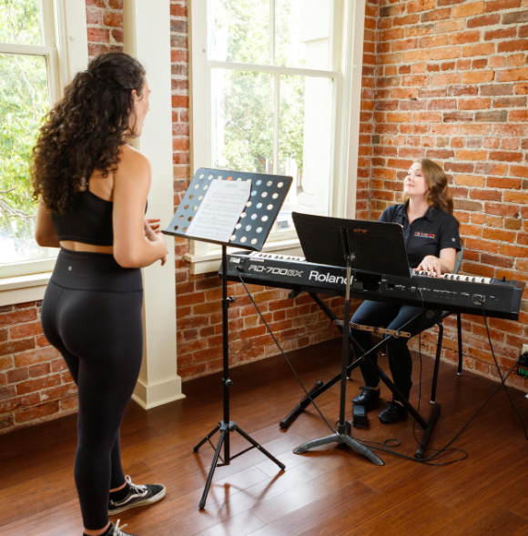 A student stands at a music stand during a private voice class.